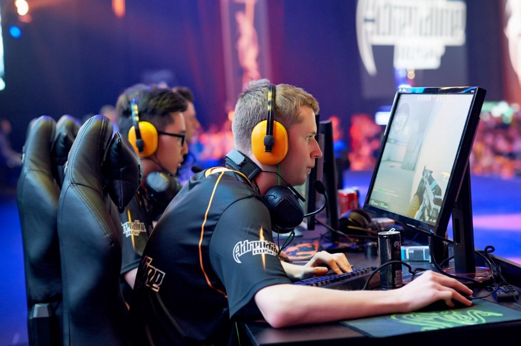 команда киберспортсменов за компьютерами на турнире с мониторами и наушниками